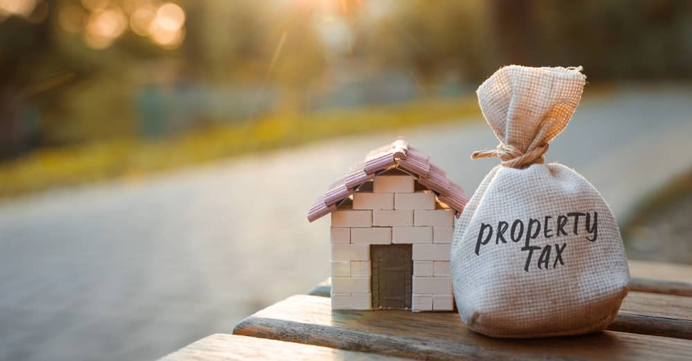 Property tax concept. Tax imposed by local governments on owners of real estate, including land, buildings, and other structures. Real estate and money