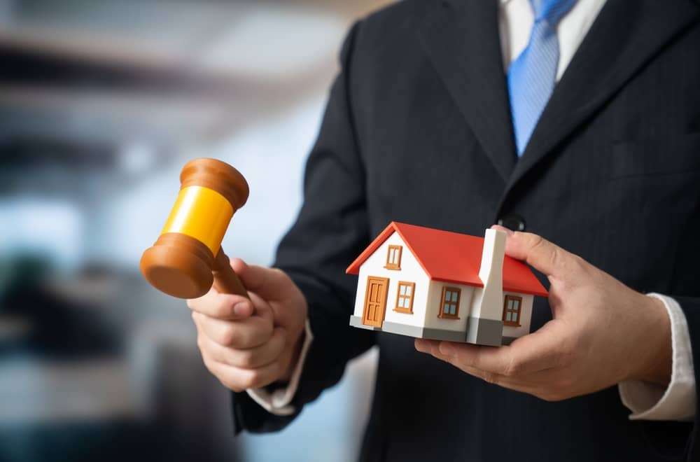 A judge holding a house and gavel possibly alluding to property justice.