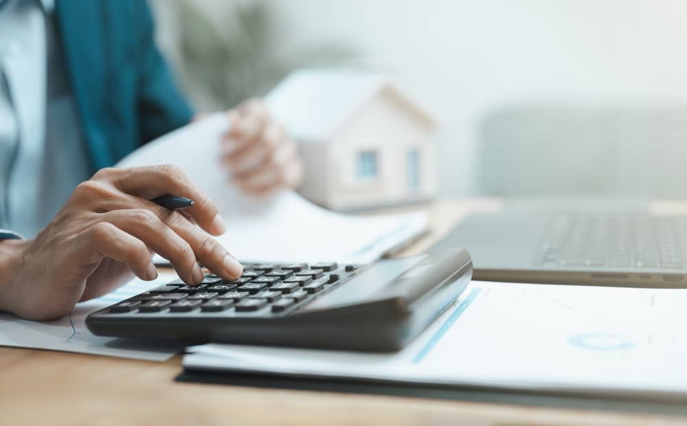 Mortgage calculator and home loan planning concept with financial documents, house model, and banking analysis, representing property investment, interest calculation, and personal finance management.