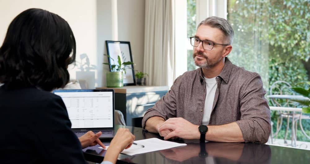 Man, meeting and realtor in office with document, application and lease form for real estate. People, consultant and laptop in workplace with contract, new listing and guidance for property purchase