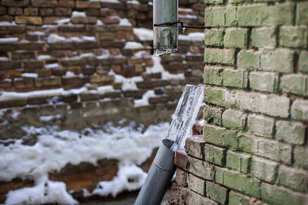 Broken frozen downspout with ice inside